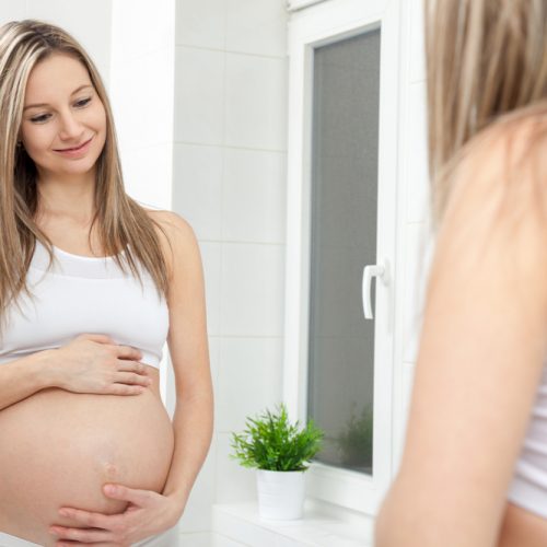 Pregnant,Woman,In,Looking,Into,Bathroom,Mirror