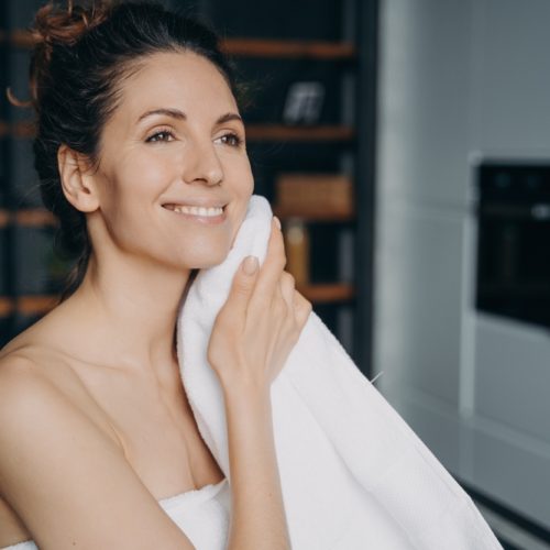 Attractive,Hispanic,Woman,Is,Wiping,Face,With,Towel,After,Washing.