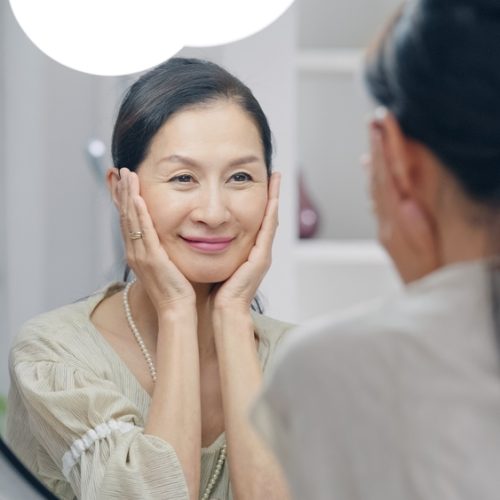 Asian,Senior,Woman,Looking,At,A,Mirror.,Anti,Aging.,Skincare.