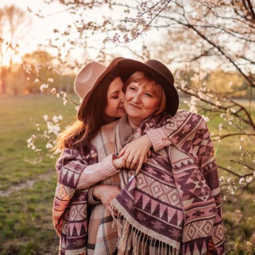 Middle-aged,Mother,And,Her,Adult,Daughter,Hugging,In,Blooming,Garden.